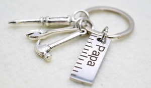 Detail of silver tool keychain with mini hammer, wrench and Papa engraved ruler plate