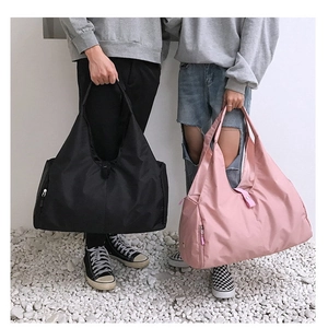 Detail view of large foldable travel bags in pink and black with side zipper pockets