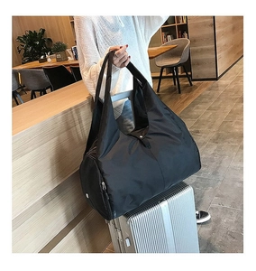 Close-up of black waterproof nylon travel bag with side zipper pocket on a wooden background
