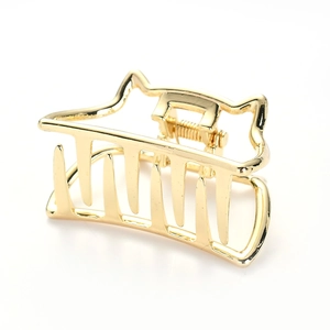 Detailed close-up of a rectangular gold metal hair claw clip with wave design on white backdrop
