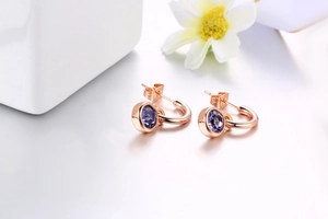 Macro shot of rose gold earrings featuring vibrant purple round cubic zirconia crystals