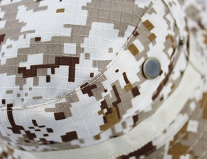 Macro shot of breathable metal vents and desert digital camo ripstop fabric on a boonie hat