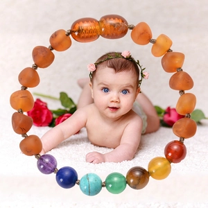 Bracelet pour bébé en ambre de la Baltique et pierres multicolores sur tapis blanc