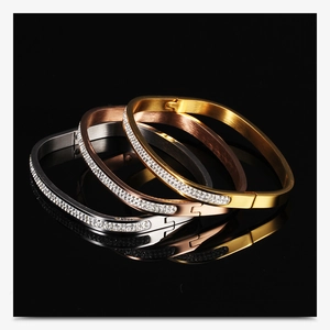 Macro view of crystal-encrusted stainless steel bangles in gold, silver, and rose gold