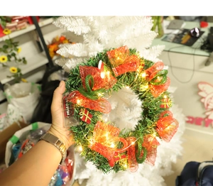 Détail de couronne de Noël verte avec nœuds en maille, cadeaux et guirlande LED chaude