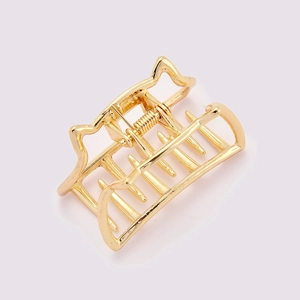 Detail of a cat-shaped golden metal hair claw clip with a polished finish on white
