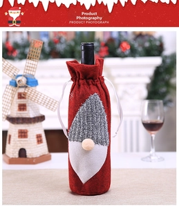 Detail of red felt Christmas gnome wine bottle cover with knit textures on a festive table