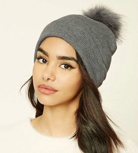 Détail du bonnet d'hiver en tricot gris avec pompon montrant chaleur et texture chic