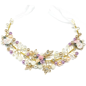 Close-up of handmade bridal headband with ceramic flowers, pearls and golden leaves