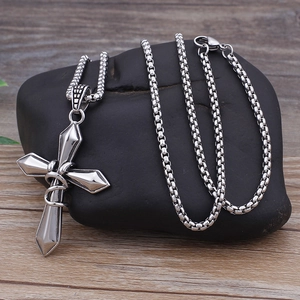 Titanium steel cross pendant necklace with silver box chain on a black stone base