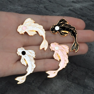Detailed view of four colorful koi fish enamel pins held in hand to show size and texture