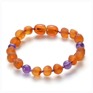 Macro detail of Baltic matte amber baby bracelet with purple amethyst beads on white backdrop