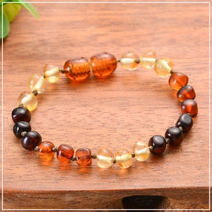 Macro shot of multi-color Baltic amber beads on a natural wooden background