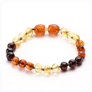 Macro detail of Baltic amber baby bracelet with multicolored round beads and barrel charms