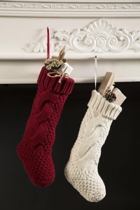 Detail of burgundy and cream knitted Christmas stockings hanging on white mantelpiece