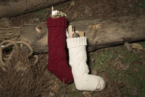 Close-up of knit Christmas stockings in red and white with festive pine cones and gift boxes