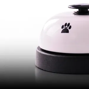 White metal pet training bell with black paw print and non-slip base for cats and dogs