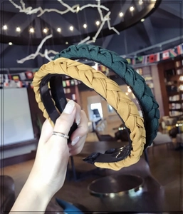 Close-up of thick braided sponge headbands in ginger yellow and dark green fabric