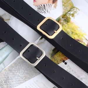 Close-up of black leather belts with square gold and silver buckles on a magazine