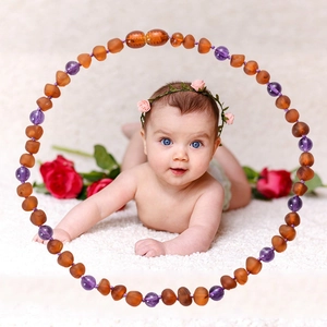 Baltic amber and amethyst baby necklace with polished beads on white carpet background