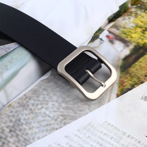 Detail shot of a black leather belt with a polished silver square pin buckle and texture