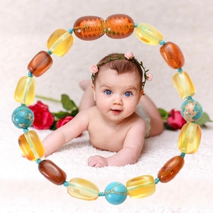 Baltic Amber and turquoise baby teething necklace on soft white plush carpet background