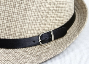 Detail of woven straw fedora featuring a black leather band and silver metal buckle