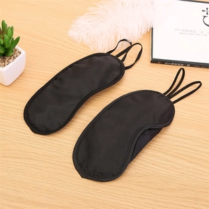 Close-up of black silk sleep masks with elastic headbands on a wooden surface