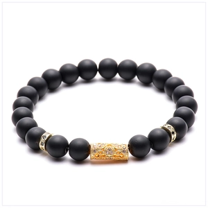 Detailed view of matte black natural stone beads and gold micro-pave zircon cylinder charm