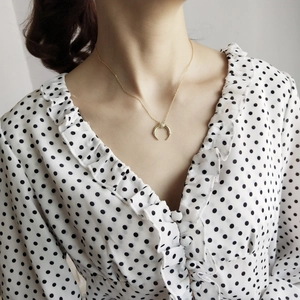 Close-up of a gold crescent moon pendant necklace with pavé zircons on a model