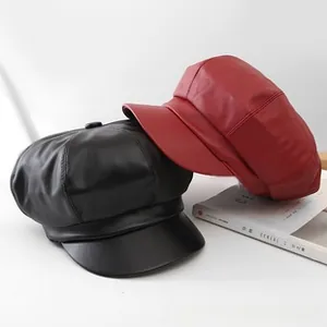 Detail of vintage leather newsboy caps in black and red colors with smooth texture