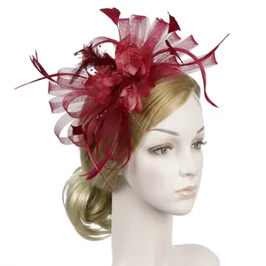 Detail of burgundy mesh fascinator with feather plumes and pearls for weddings