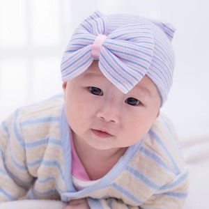 Soft knitted baby hospital hat with blue stripes and a large decorative pink ribbon bow