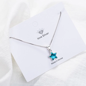 Elegant silver star necklace with deep blue crystal pendant on white display card