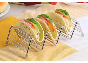 Close-up of stainless steel taco holder with four filled tacos on a checkered placemat