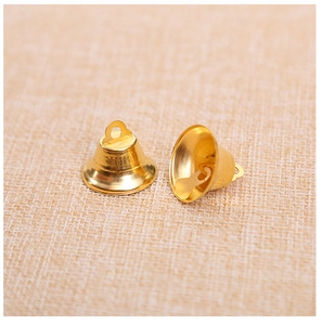 Macro shot of two shiny gold decorative bells on textured fabric for DIY Christmas crafts