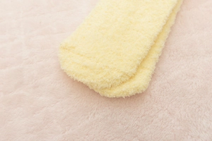 Close-up of soft yellow coral fleece fabric showing fluffy texture of a warm fuzzy sock