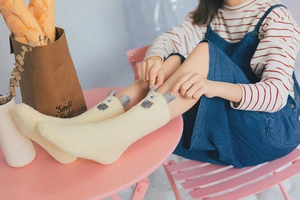 Detail of light yellow coral fleece socks with cute cartoon alpaca ears and face