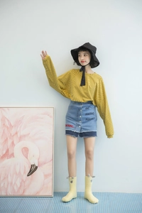 Detail of yellow striped crew socks worn with denim skirt and casual sneakers