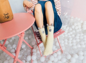 Close-up of warm coral fleece crew socks with cute alpaca monster embroidery detail