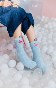 Close-up of fluffy blue coral fleece socks with cute cartoon monster ears in white balls