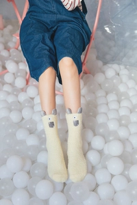 Detail showing plush beige crew socks with 3D cartoon alpaca ears in a ball pit