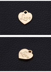 Close-up of golden heart pendant with Love engraving on black leather background