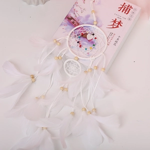 Detail of white dream catcher with soft feathers, wood beads, and a heart pendant