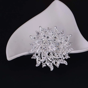 Macro detail of silver petal brooch with sparkling rhinestones on black background