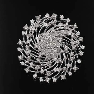 Detail view of silver alloy starburst brooch with sparkling rhinestones on black background