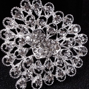 Detailed close-up of a heart-shaped rhinestone brooch with intricate hollow patterns