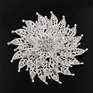 Detail of silver alloy floral brooch with intricate hollow petals and clear rhinestones