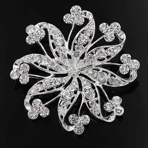 Detail of silver alloy flower brooch with sparkling clear rhinestones on black background