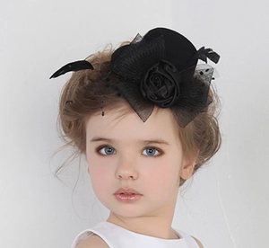 Detail of girls mini black top hat with mesh veil, feathers and floral accents